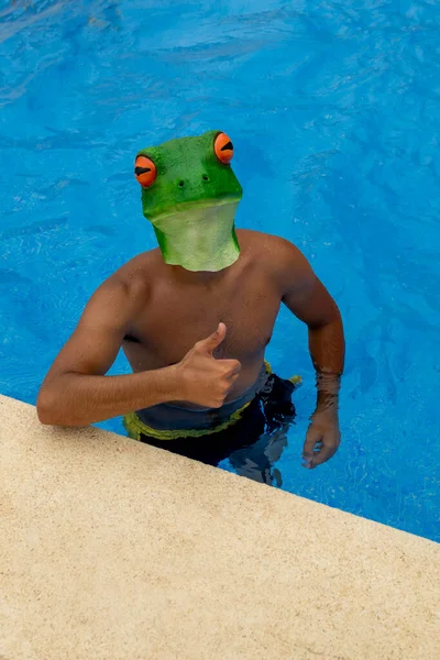 Junger kaukasischer Mann mit Badeanzug und Froschmaske auf dem Kopf am Rande eines Swimmingpools, der mit der Hand Okay gibt — Stockfoto