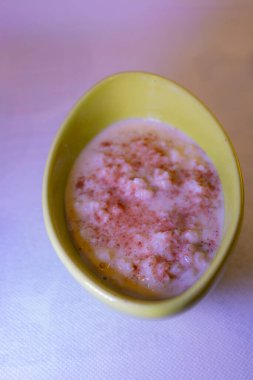 Hafif desenli masa örtüsü üzerine tarçın serpiştirilmiş sütlaçlı yeşil seramik kase..