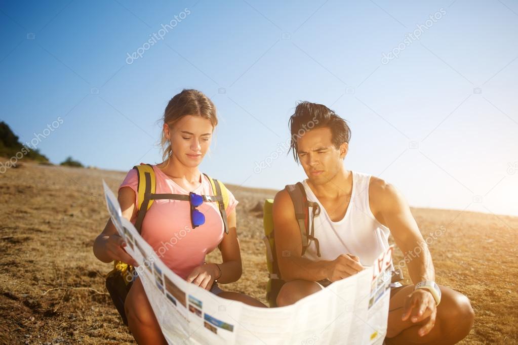 Couple of a tourists are searching new way during their walking in the fresh air in sunny summer day