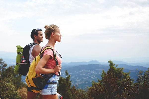 Dos excursionistas con mochilas están descansando después de caminar activamente en las montañas durante su fin de semana de verano en el extranjero —  Fotos de Stock