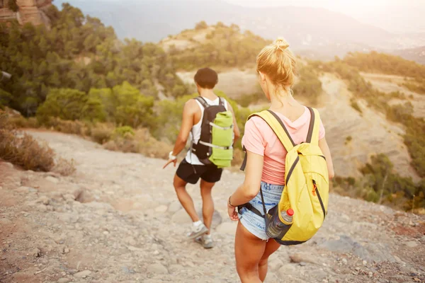 Dos excursionistas con mochilas en la espalda están explorando nuevos lugares durante su viaje increíble —  Fotos de Stock