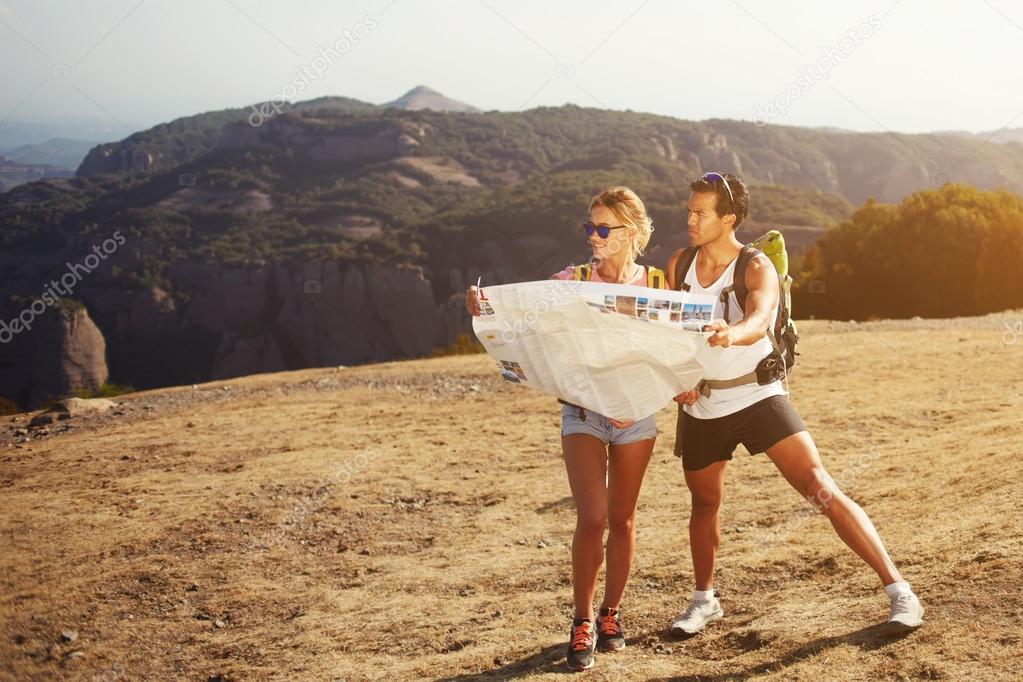 Man and women travelers are holding location map during their hiking in mountain at weekend