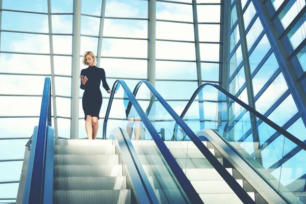 Woman reading message on phone on escalator — Stok fotoğraf