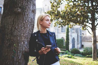 Young charming woman tourist with cell telephone in hands resting after tour 