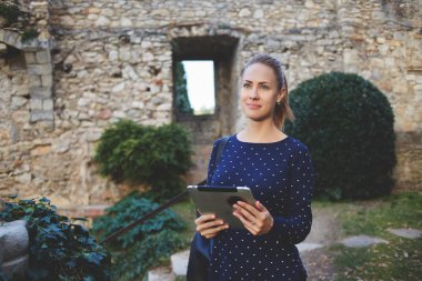 Woman tourist is using touch pad for navigation during her walking tour in old city