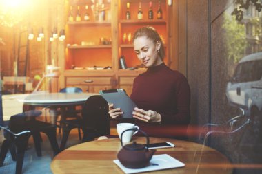 Modern kahve dükkanında otururken çok kadın freelancer iş dokunmatik yüzey üzerinde 