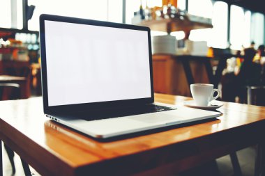 Taşınabilir net-kitap modern kahve dükkanında tahta bir masanın üzerinde yatan hücre telefon ile 