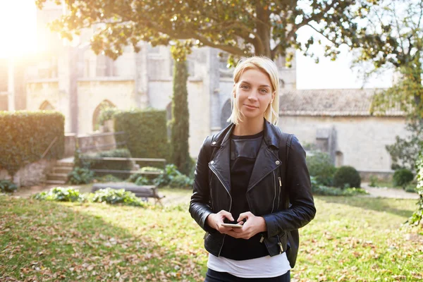 Schönes Hipster-Mädchen hält Handy in der Hand und schaut in die Kamera — Stockfoto