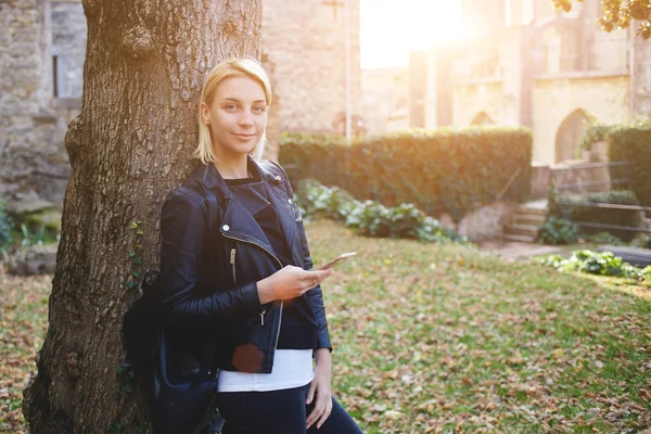 Молодая студентка пользуется мобильным телефоном во время перерыва между лекциями в колледже — стоковое фото