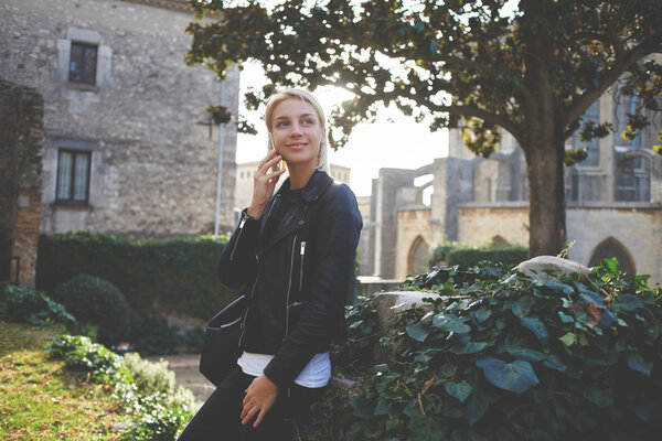 Hipster girl in good mood is phoning via cell telephone during spare time