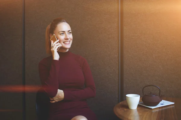 Junge Frau telefoniert mit Handy, während sie sich im Café entspannt — Stockfoto