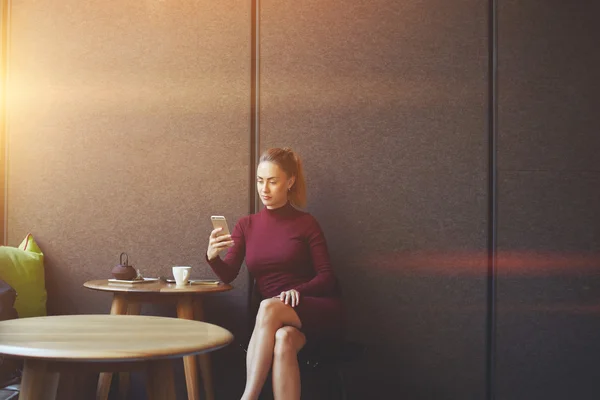 Привлекательная женщина смотрит видео или читает бизнес-блог в сети по сотовому телефону — стоковое фото