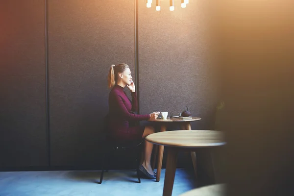 Femme d'affaires confiante utilisant son téléphone intelligent tout en se relaxant après la journée de travail dans un café — Photo