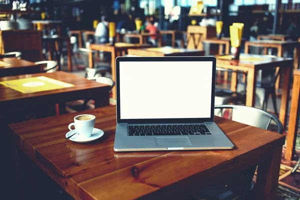 Öppna bärbar dator och kopp kaffe liggande på ett träbord i café bar inre — Stockfoto