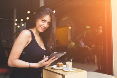 Elinde dijital tablet ile modern iş kadını modern kahve dükkanı iç oturuyor. 
