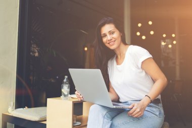 Gülümseyen hipster kız sohbet için internete bağlanmak için dizüstü bilgisayar kullanıyor