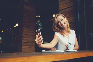 Sevimli gülümseme kafede dinlenme sırasında ona akıllı telefon kendi kendine fotoğraf yapma ile güzel kadın 