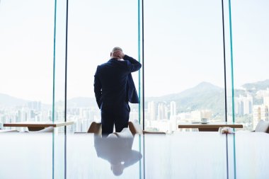 Businessman is standing near office window with view of Hong Kong city clipart