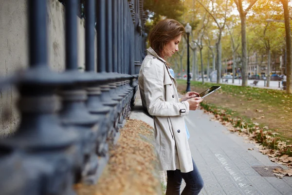 Woman is playing games on digital tablet, while is waiting friend outdoors — Stock Photo, Image