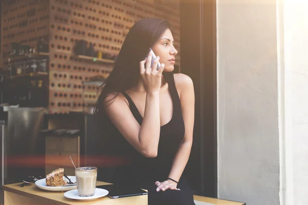 Bastante latina teniendo conversación móvil mientras descansa en la cafetería de la acera después de ir de compras al centro comercial — Foto de Stock