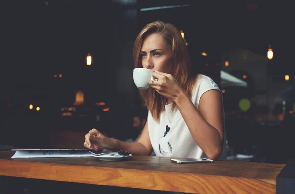 Young pretty European woman drinking cappuccino while relaxing in modern cafe bar after work day — Stock Photo, Image