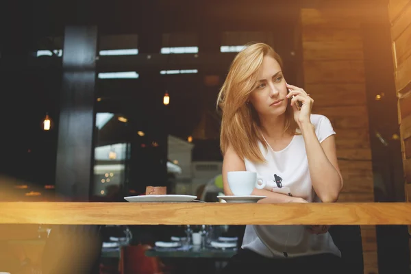 Atraente chateado feminino chamando com telefone inteligente durante o café da manhã no café — Fotografia de Stock