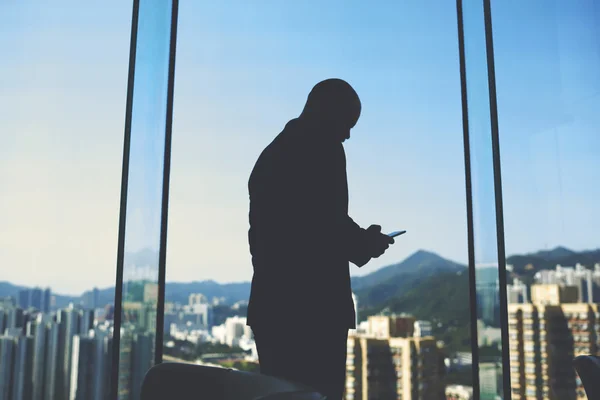 Homme gestionnaire est debout dans son bureau près de la grande fenêtre avec vue sur le quartier des affaires en Chine — Photo