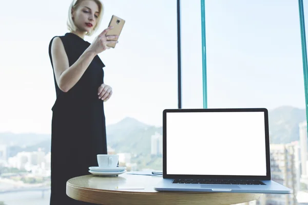 Jovem advogada bem sucedida está lendo mensagem de texto no telefone celular, enquanto está de pé no interior do escritório moderno — Fotografia de Stock
