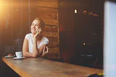 Yaz günü yürüdükten sonra dinlenirken cep telefonu ile arayan gülümseyen hipster kız 