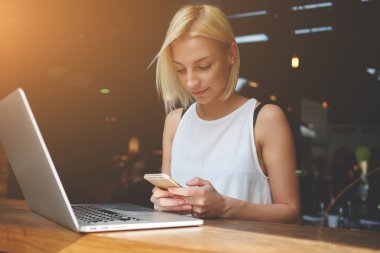 Taşınabilir net kitap üzerinde işten sonra rahatlatıcı iken cep telefonu kullanarak Pretty Avrupalı kadın 