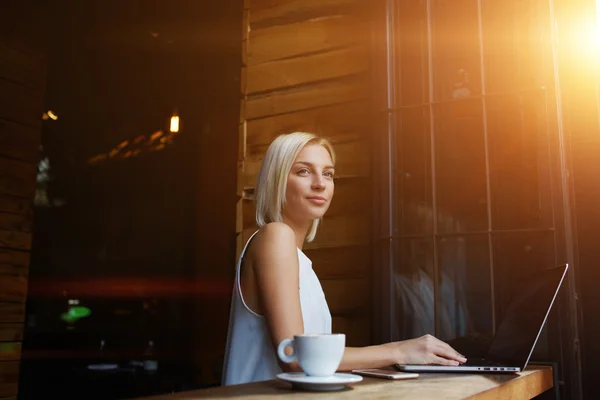 Thoughtful attractive female freelancer using portable net-book for distance work — Stock Photo, Image