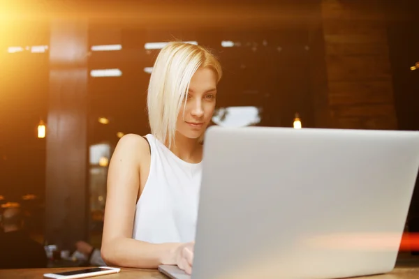 Schöne blonde Studentin, die vor ihren Vorlesungen an der Universität am Laptop arbeitet — Stockfoto