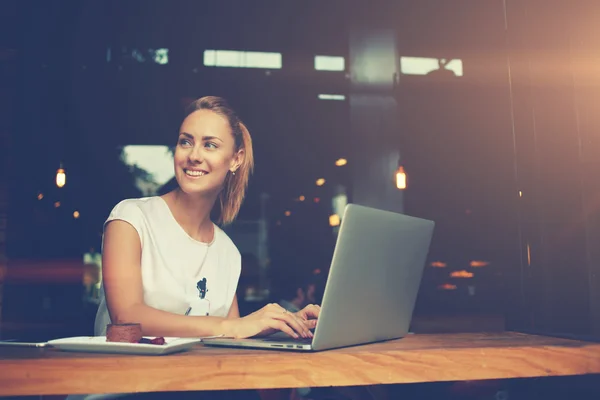 Mulher atraente com belo sorriso sentado com net-book portátil no café — Fotografia de Stock