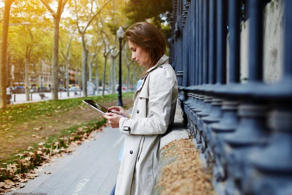 Γυναίκα ντυμένη με ελατήρια ρούχα διαβάζει πληροφορίες στο διαδίκτυο μέσω ψηφιακού tablet — Φωτογραφία Αρχείου