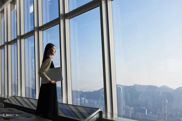 Mujer de negocios satisfecha de pie con el ordenador portátil — Foto de Stock