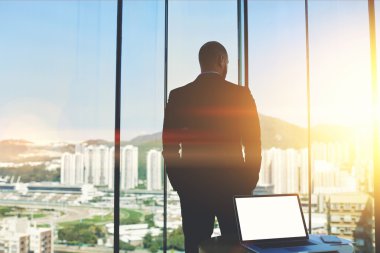 Business man standing near skyscraper window 
