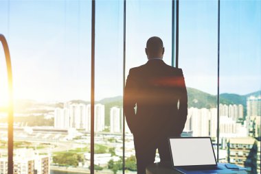 Silhouette of business man watching in window 
