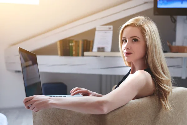 Mujer joven programador remoto está posando para la cámara durante el trabajo en el ordenador portátil en su moderno interior de oficina hipster —  Fotos de Stock