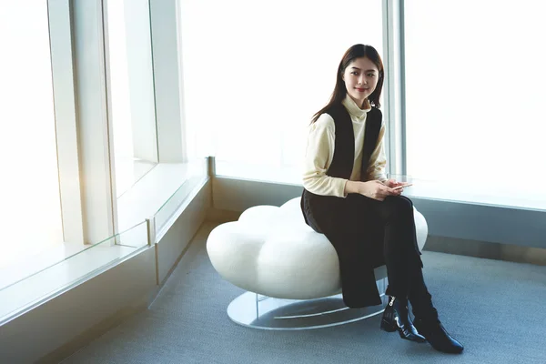 Young Japanese businesswoman with mobile phone in hands is waiting international partners in airport hallway — стокове фото