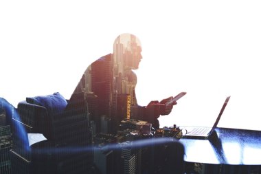 Young successful male entrepreneur is working on digital tablet and laptop computer