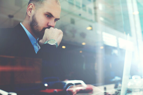 Successful lawyer is using portable net-book  while is sitting in modern coffee shop interior