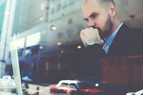 Confident businessman with serious face is using net-book during coffee break — Stock Photo, Image