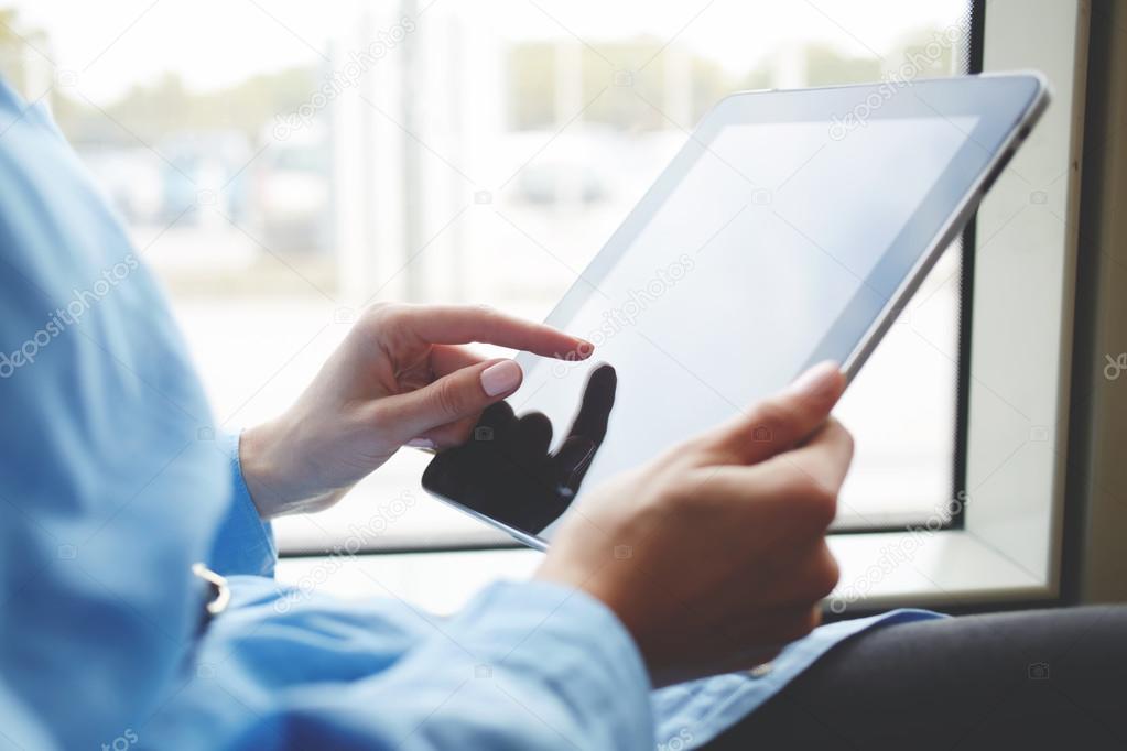 Closeup image of woman is booking on-line via portable digital tablet. Closely of female is searching needed file on her touch pad with copy space screen.