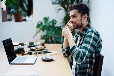İyimser etnik sakallı bir adamın kahve molasında gülümseyen ve yüzünü çeviren bakışları.
