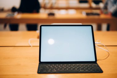 Modern ambardaki ahşap masa üzerinde bulunan klavye ve beyaz ekran tablet bilgisayarının modern açılı modeliName