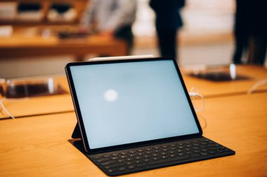 Boş ekran klavyesi ve ışık depolarındaki ahşap masaya yerleştirilmiş modern tabletin yüksek açılı modeli
