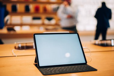 Beyaz ekran klavyeli modern tabletin yüksek açılı modeli ve ışık depolarındaki ahşap masa üzerine yerleştirilmiş stil