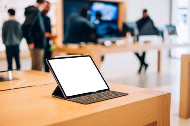 Elektronik mağazadaki ahşap masaya yerleştirilmiş boş ekran klavyesi ve stili olan modern tabletin yüksek açılı modeli