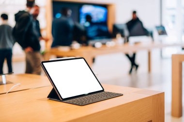 Beyaz ekran stili ve klavyeli modern tabletin, ışık depolarındaki ahşap masaya yerleştirilmiş yüksek açılı modeli.