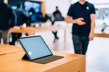 Boş ekran klavyesi ve stili ışık deposundaki kereste masasına yerleştirilmiş modern tabletin yüksek açılı modeli